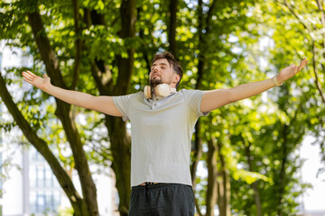 Keep calm down, relax. Bearded man jogger meditating, breathes deeply with mudra gesture, praying eyes closed, concentrated thoughts, peaceful mind outdoors. Guy exercising surrounding trees in park.