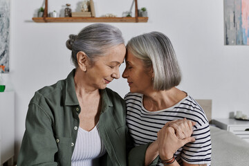 A mature lesbian couple embraces in their modern apartment, showcasing the enduring love and intimacy shared in their relationship.