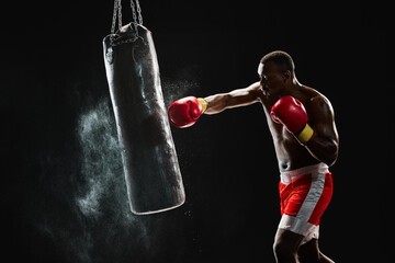 African man, muscular fighter in mid-punch, showcasing his training routine isolated on black...