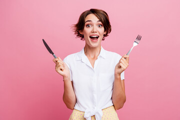 Photo of young hungry lady holding fork knife preparing to eat breakfast open mouth wear white new...