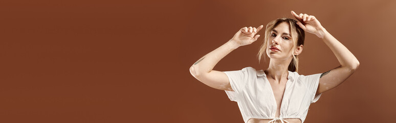 A young woman with vitiligo poses confidently in a white summer outfit against a beige background.