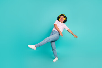 Photo of funny youth girl with curly hair enjoying music her new loud stereo earphones dance boogie woogie isolated on cyan color background