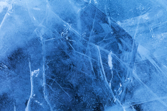 Beautiful crystalline ice texture. Cold background of blue ice with cracks and lines of icy surface of frozen Baikal Lake on winter. Unique ice pattern. Top view, flat lay, mockup, copy space