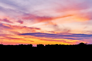 Dusk, sunset sky clouds in the evening with colorful orange, yellow, pink and red sunlight and dramatic storm clouds in the twilight sky, landscape horizon, nature, summer background.