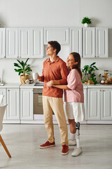 A couple stands in their kitchen, smiling and enjoying a cup of coffee.