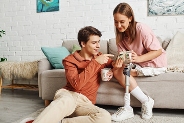 A woman with a prosthetic leg and her boyfriend enjoy a cup of coffee together in their living room.