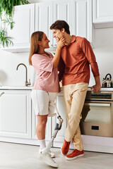 A woman with a prosthetic leg and her boyfriend share a tender moment in their kitchen.