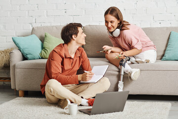 A woman with a prosthetic leg and her boyfriend working together at home.