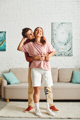 A woman with a prosthetic leg embraces her boyfriend in a living room.