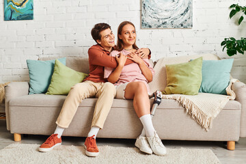 A woman with a prosthetic leg embraces her boyfriend while sitting on a couch.