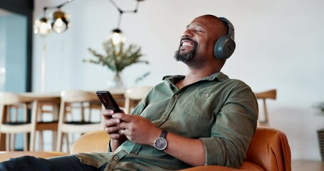 Black man, relax and headphones with music on phone for streaming video, podcast and networking on social media. African, male person and mobile for listening, playlist audio and dancing at home - Powered by Adobe