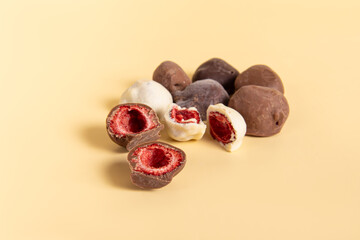 Dried strawberries in chocolate on beige background. Strawberries in dark, milk and white chocolate