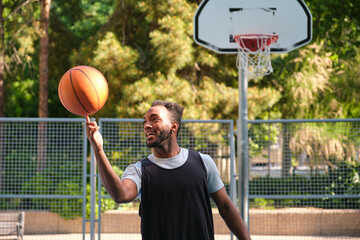 Young basketball player spinning a ball on his finger while standing on a basketball court