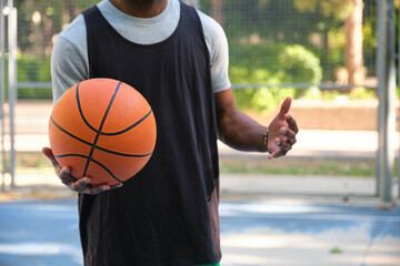 Unrecognizable basketball player is explaining tactics to his team during training on a sunny day