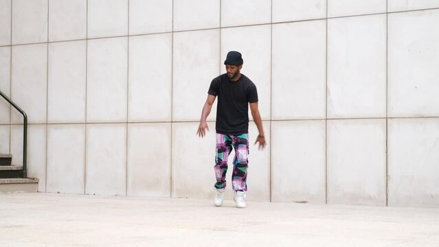 Street dancer showcasing breakdance moves against urban wall backdrop. Includes spins, flips, and ground choreography