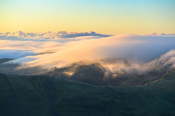 Obraz premium Clouds above the mountains on a beautiful sunny morning seen from Helvellyn in The Lake District, UK.