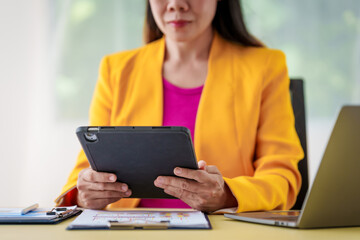 An Asian businesswoman is diligently working at an accountant's desk, surrounded by financial documents and a laptop, meticulously analyzing data to ensure accurate and efficient financial management.