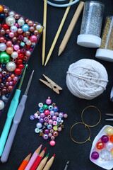 Colorful beads, coloring pencils, glitter, needles, string, hoop, tape and scissors on dark...