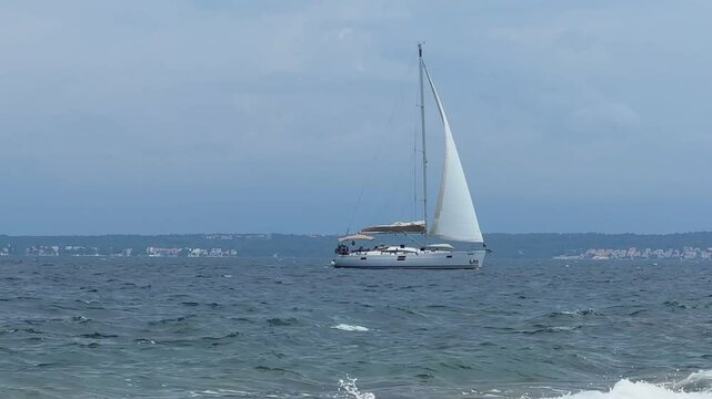 Boat with a sail on the birch water of the Adriatic sea. A white sailboat sails on the blue sea. Sailing holidays off the coast of Croatia, Preko island, June 27, 2024
