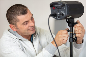 man adjusts lighting in photography studio