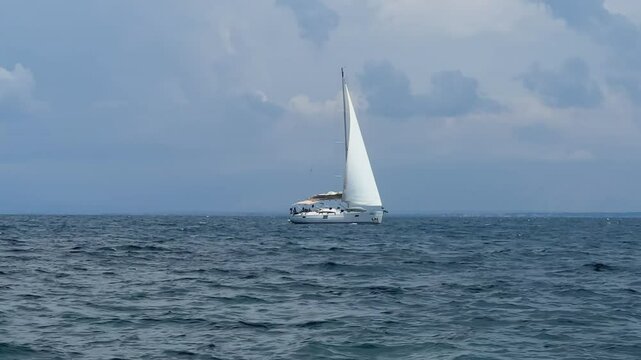 Boat with a sail on the birch water of the Adriatic sea. A white sailboat sails on the blue sea. Sailing holidays off the coast of Croatia, Preko island, June 27, 2024