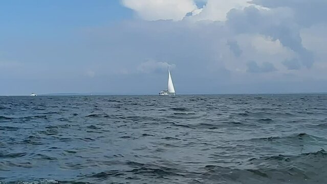 Boat with a sail on the birch water of the Adriatic sea. A white sailboat sails on the blue sea. Sailing holidays off the coast of Croatia, Preko island, June 27, 2024