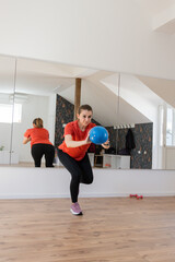 Woman In A Fitness Studio Performing An Exercise With A Blue Ball, Reflected In A Large Mirror	
