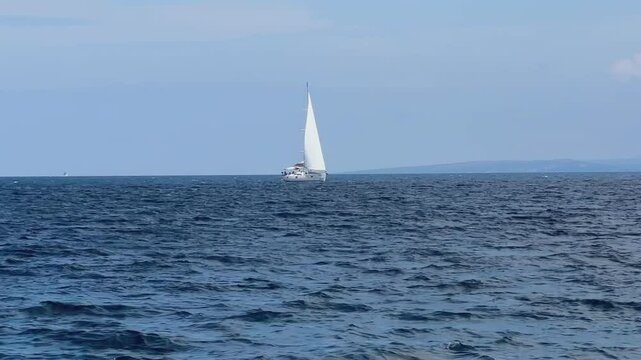 Boat with a sail on the birch water of the Adriatic sea. A white sailboat sails on the blue sea. Sailing holidays off the coast of Croatia, Preko island, June 27, 2024