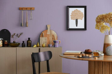 Dinning room and kitchen interior with mock up poster frame, round table, rattan chair, beige commode, vase with dried flowers, cup, pitcher and kitchen accessories. Home decor. Template.