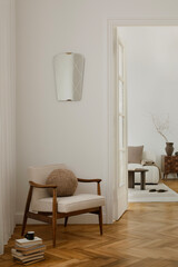 A stylish, minimalist living area featuring a mid-century modern armchair with a cozy cushion, a...