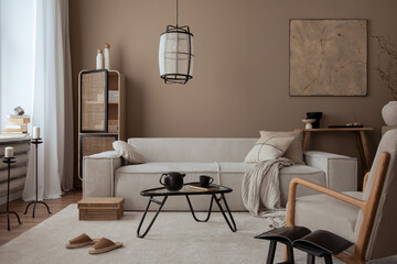 Elegant composition of warm living room interior with mock up poster frame, modular sofa, travertine coffee table, gray armchair, rattan sideboard, lamp and personal accessories. Home decor. Template.