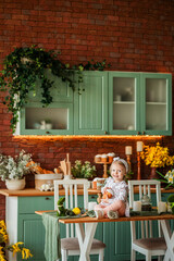 a little girl sits on the table and holds a paska in her hands