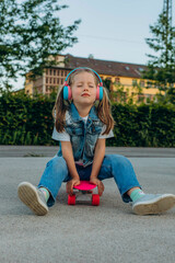 kid girl playing surf skate or skateboard in headphones