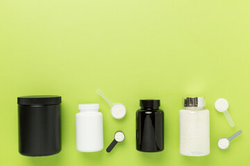 Jars with protein powder on color background, top view. Sports nutrition concept