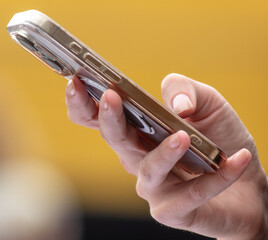 Phone in the hands of a woman on a yellow background