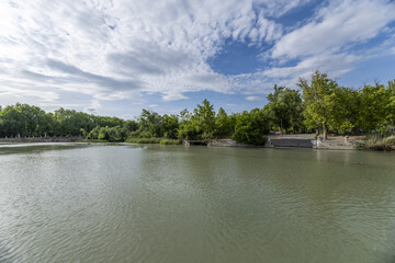 The landscape is surrounded by green hills and wooded valleys, creating an idyllic natural setting.