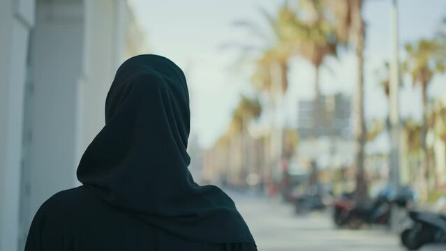 Cinematic image of a beautiful woman from Dubai wearing black abaya dress and walking in the city center and doing shopping.