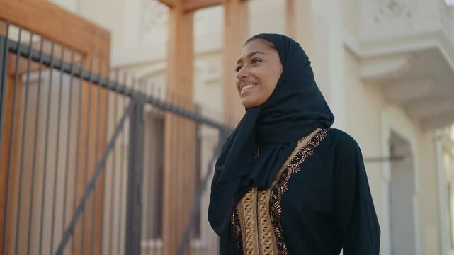 Cinematic image of a beautiful woman from Dubai wearing black abaya dress and walking in the city center and doing shopping.