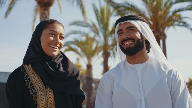 Cinematic image of a young couple from the united arab emirates spending time outdoor. Man and woman with traditional emirati kandura and abaya walking in the city center and doing shopping.