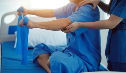 Close up hand patient doing stretching exercise with a flexible exercise band and a physical therapist hand to help in clinic room.