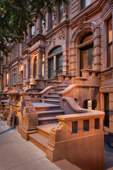 Evening view of iconic brownstones with stoop steps in New York City's Upper West Side, Manhattan. This row of brownstones is located in Central Park West Historic District