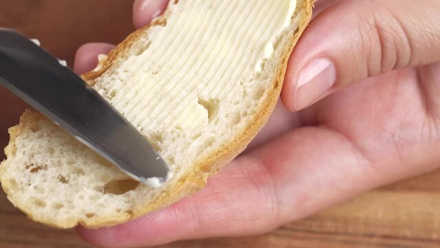 Woman spreading soft butter on slice of bread close up. Spreading cream cheese on bread.