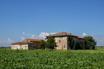 Abandoned farmhouse with cultivated field under blue sky