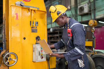 Industrial Technician Using Laptop at Machinery
