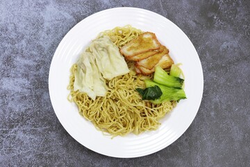 Egg Noodle with Pork Wonton and BBQ Pork in white plate, close up photo top view
