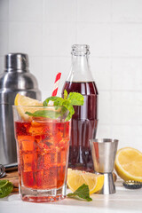 Cola and wine sweet sour alcoholic drink, Kalimotxo or calimocho boozy fizzy cocktail with ice cubes, lemon and mint, copy space