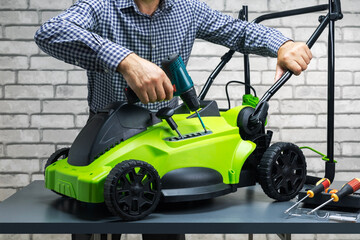 man, serviceman is repairing a lawnmower at workshop.