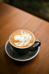 a cup of hot latte art coffee on wooden table