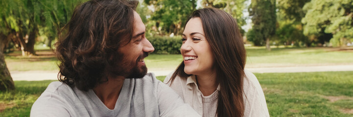 Happy smiling couple talking while sitting on blanket in park, Close-up, panorama