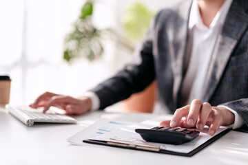 A person is sitting at a desk with a calculator and a keyboard